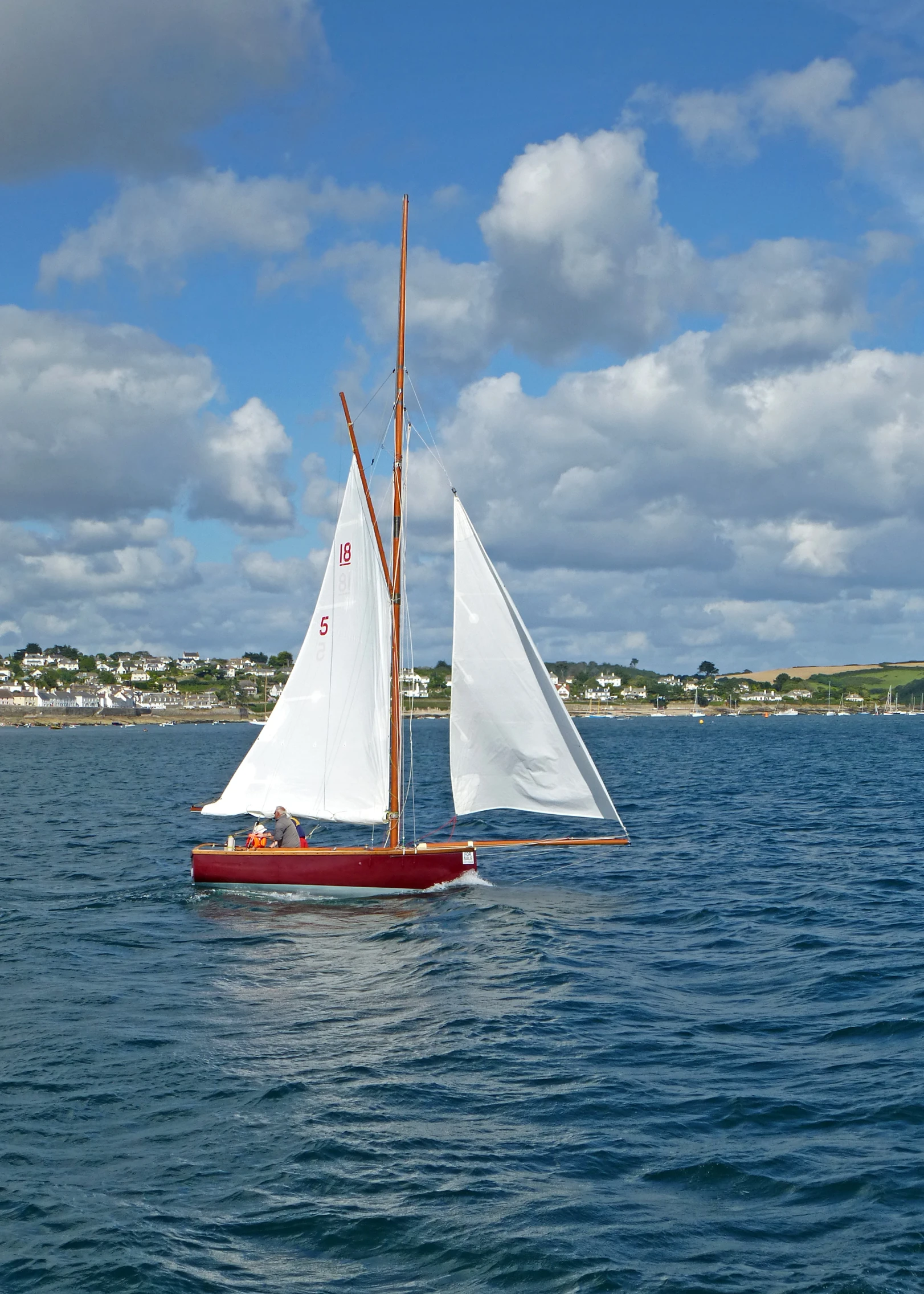 small sail boat sailing through open waters on a clear day