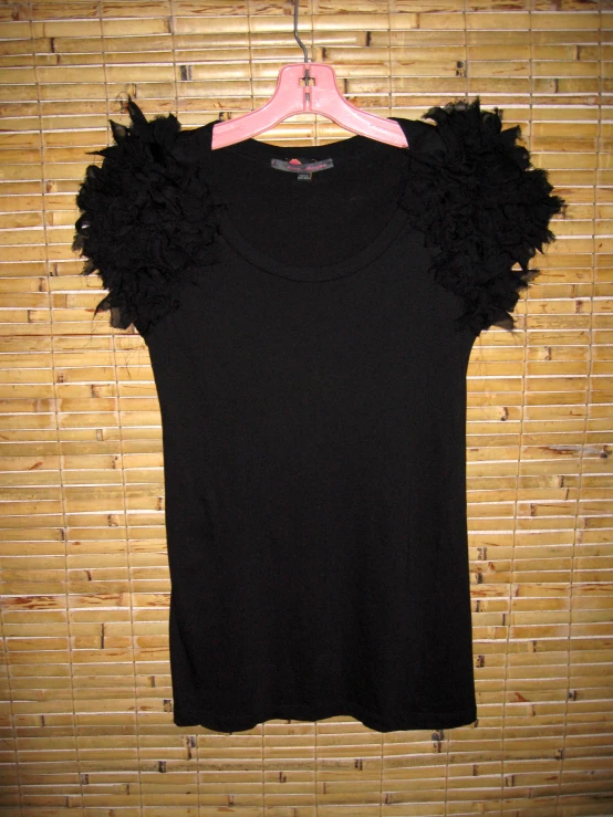 a top that is hanging up on a bamboo wall