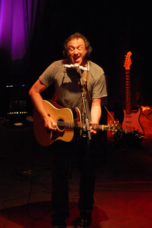 a man in a gray shirt holding a guitar