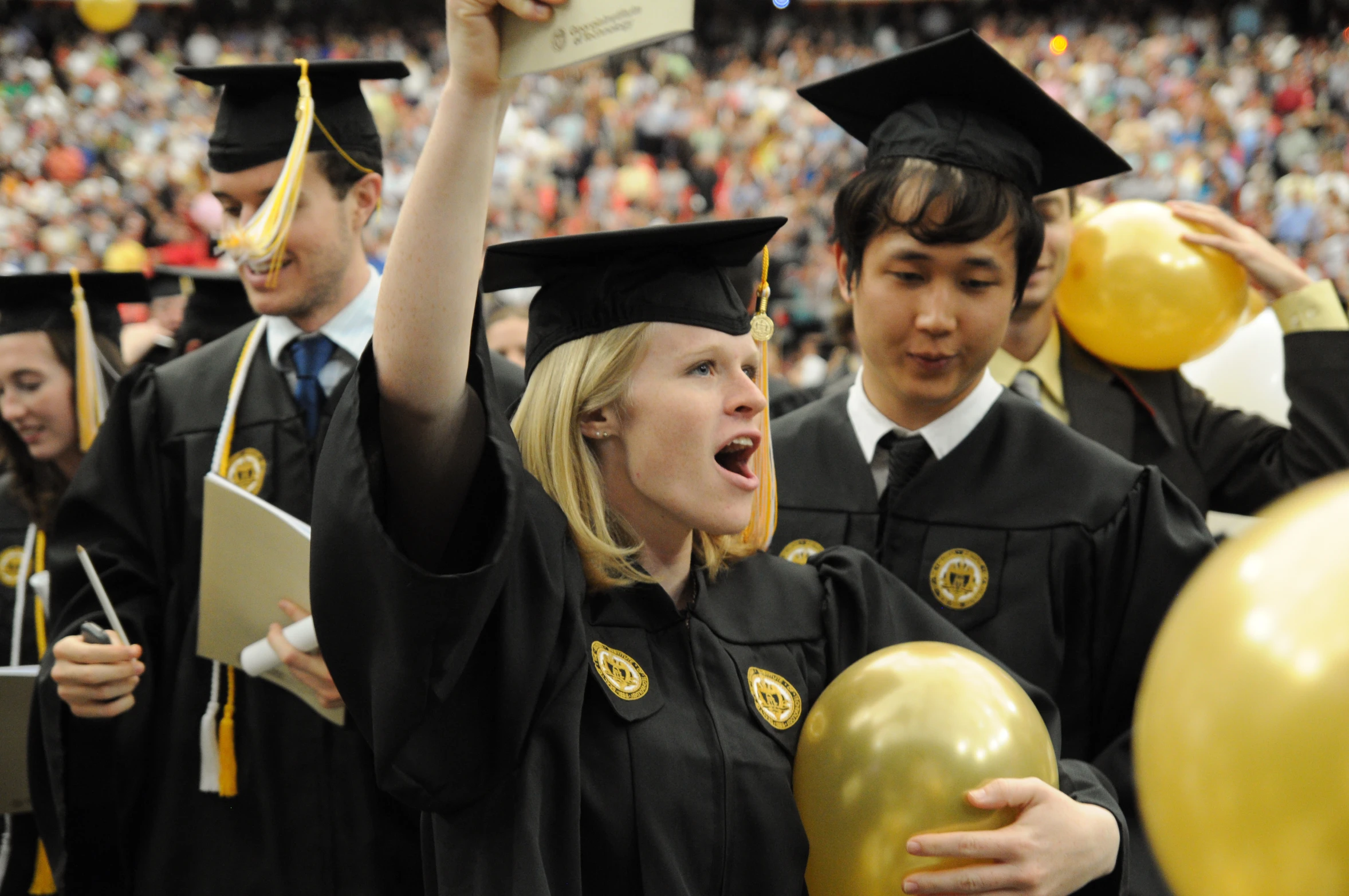 several graduates are holding up gold balloons and confetti