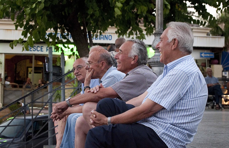 a group of people sitting on a bench on a sidewalk