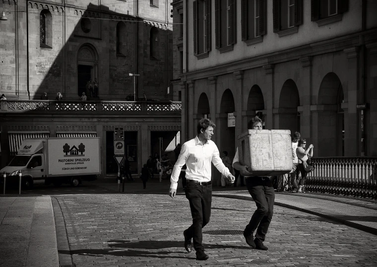 two people carrying boxes up an urban street