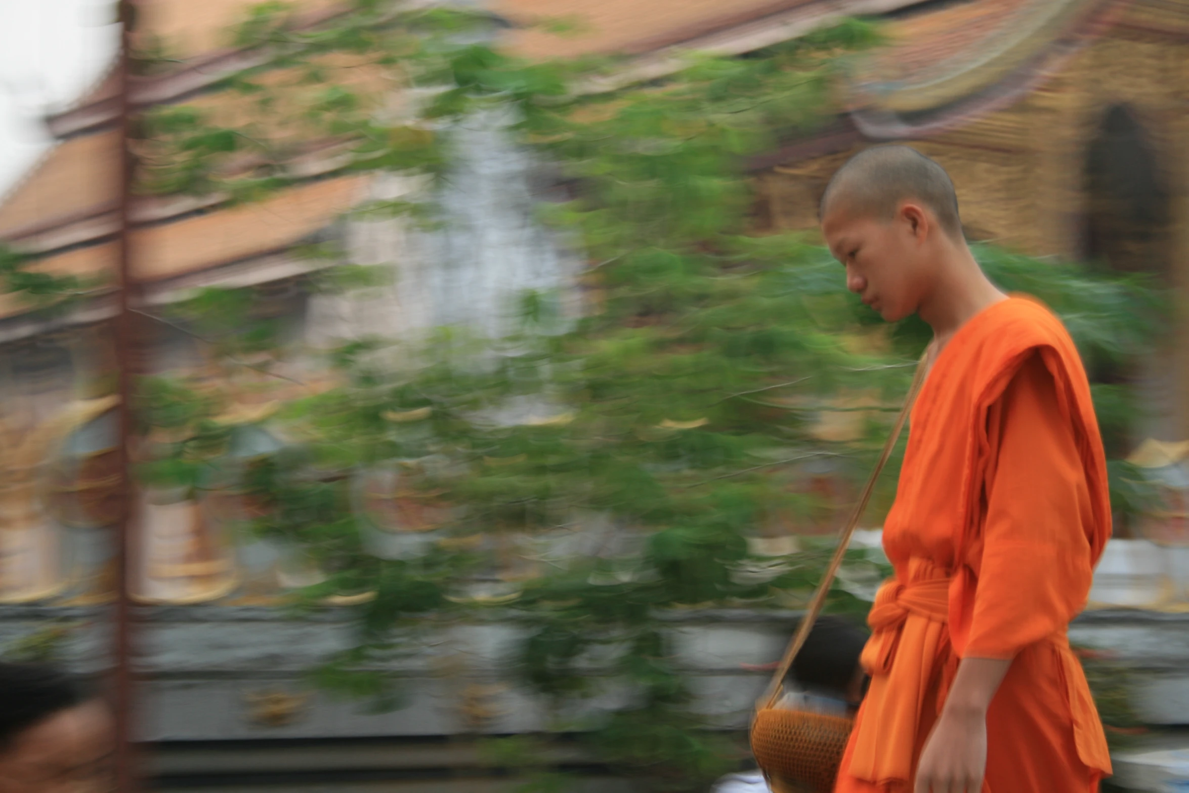 a monk walking down a sidewalk with other people