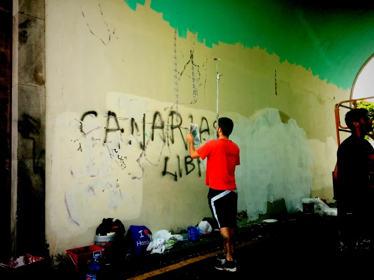 a person in an orange shirt writing graffiti on the wall