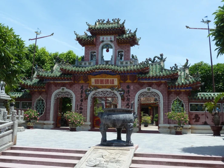 an ornamental building with statues and flowers around it