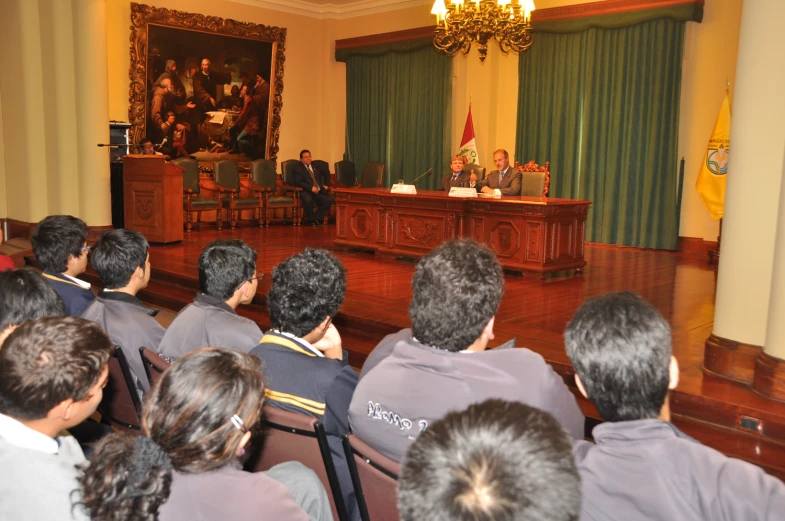 group of people seated in front of a microphone while talking to one man