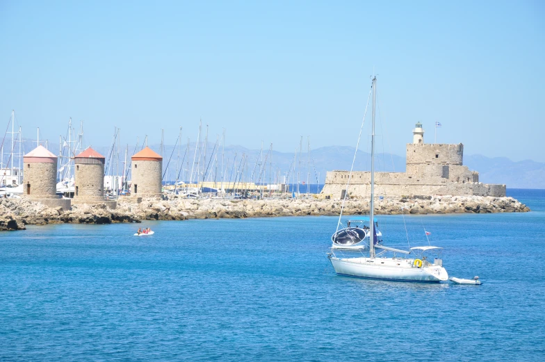 several sail boats in the water near a wall