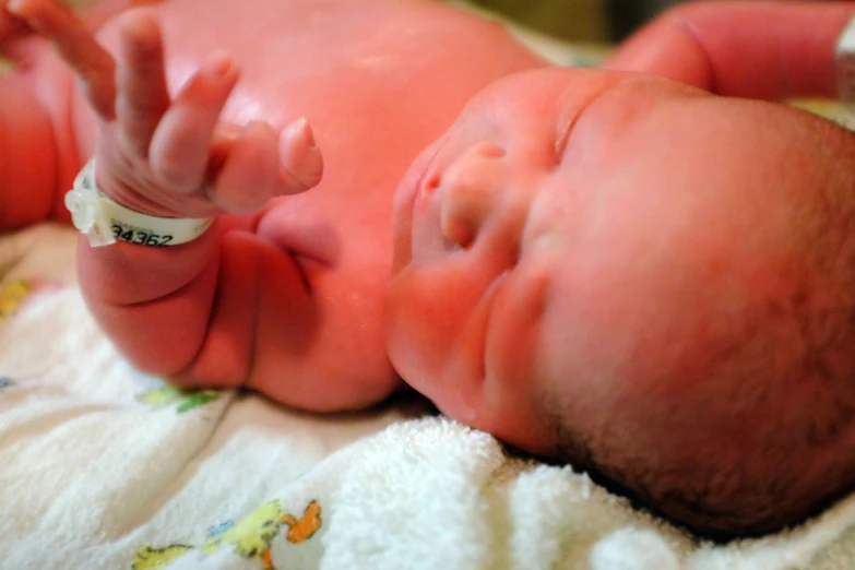 a sleeping baby is in a bed with his hand extended up