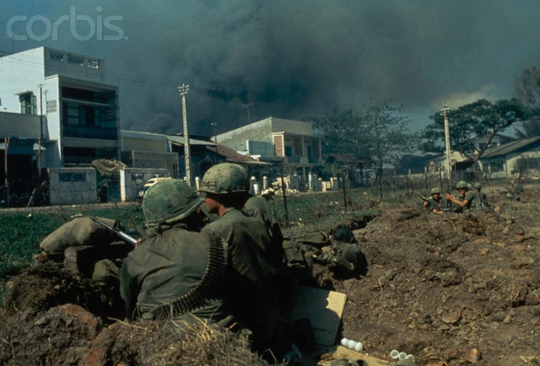 a group of soldiers are laying on the ground and watching a fire