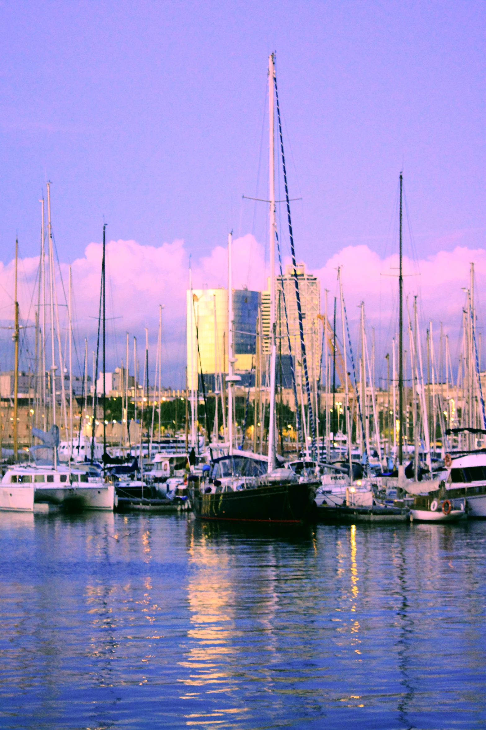 a view of several boats in the water, in front of some buildings and a few buildings