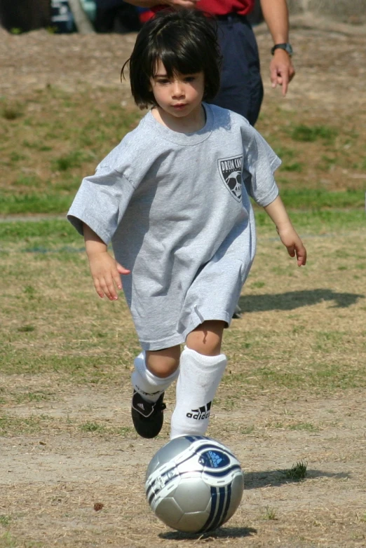 a child playing with a soccer ball on the ground