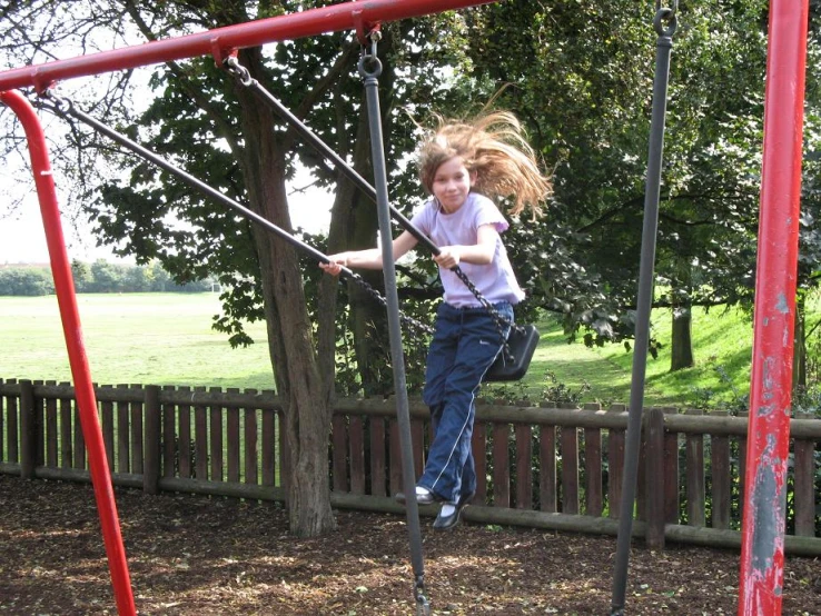 the young child is swinging on the play ground