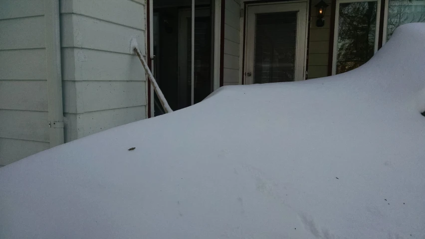 the door of a home is partially covered with snow