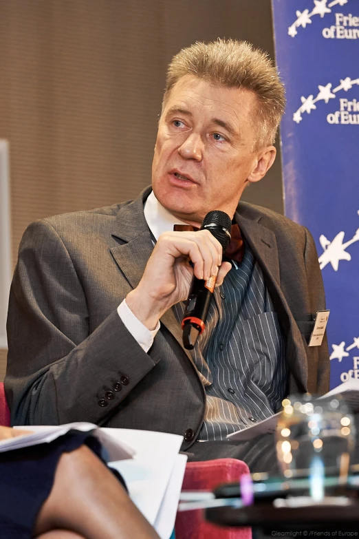 a man sitting at a table talking into a microphone