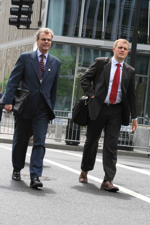 two business men in business attire cross a street