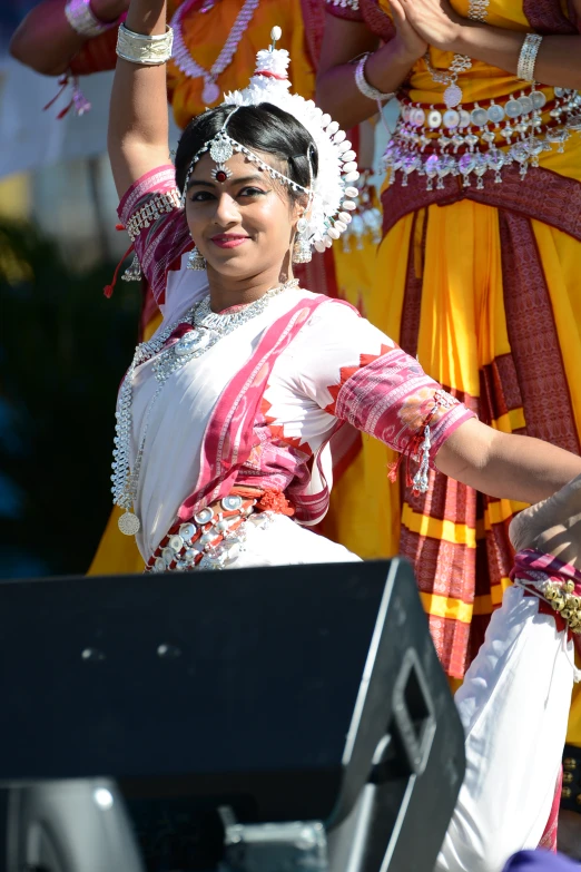 women dancing in bright clothing, white pants and headdress