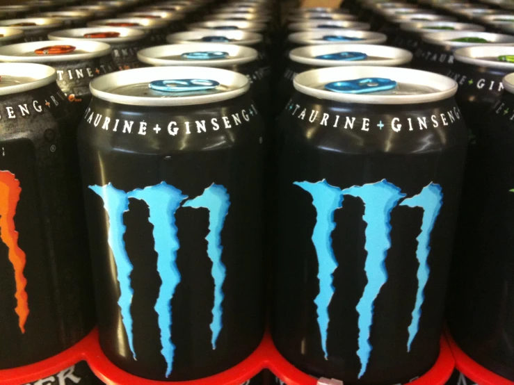 a row of black cans with blue and orange monster energy