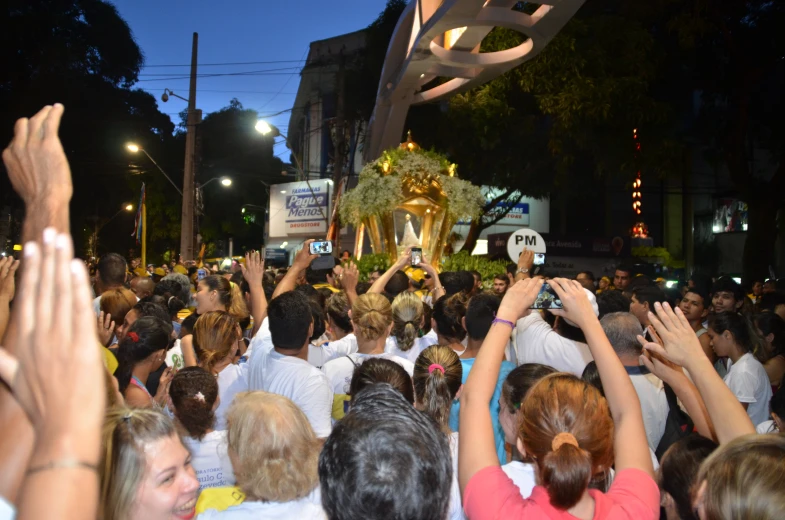 several people are gathering in a crowded street and one person holding up a trophy