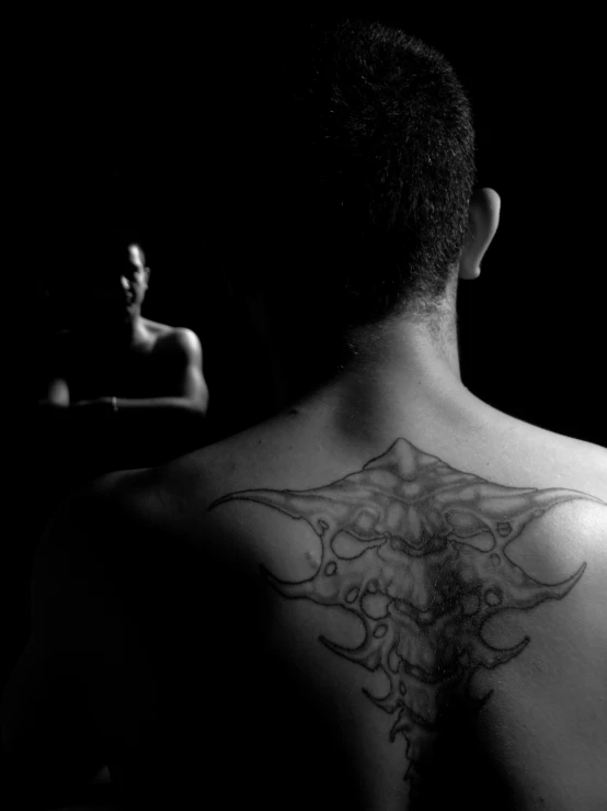 a black and white po of a man with a tattoo on his back