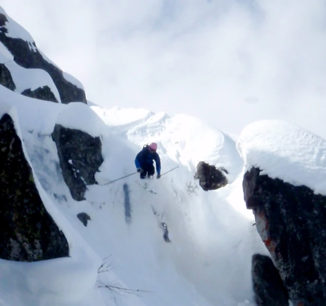 two climbers walking up the side of a mountain with snow