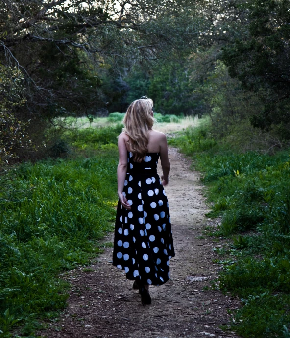 a woman walks along a path while wearing a dress
