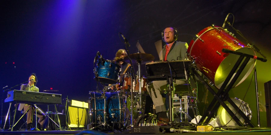 several musicians and drummers performing in front of bright lights