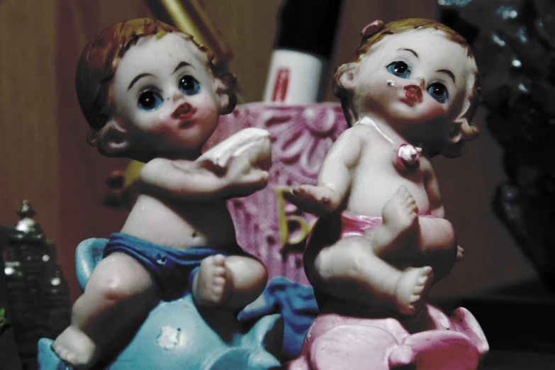 two baby doll statues sitting next to each other