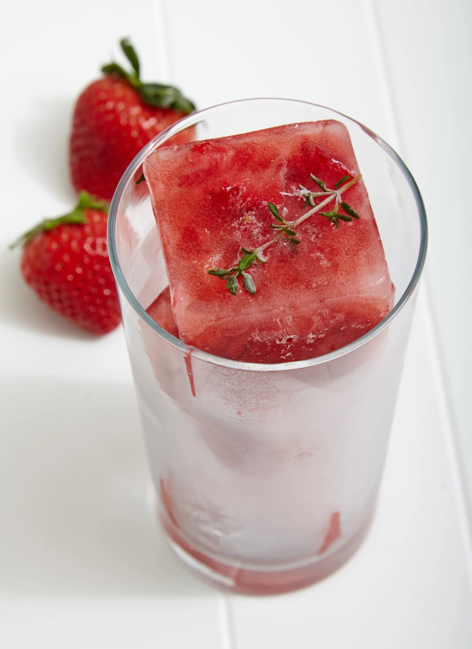 a strawberry and water drink with ice cubes in it