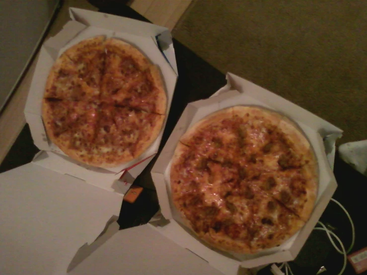 two pizzas are in the boxes on the table
