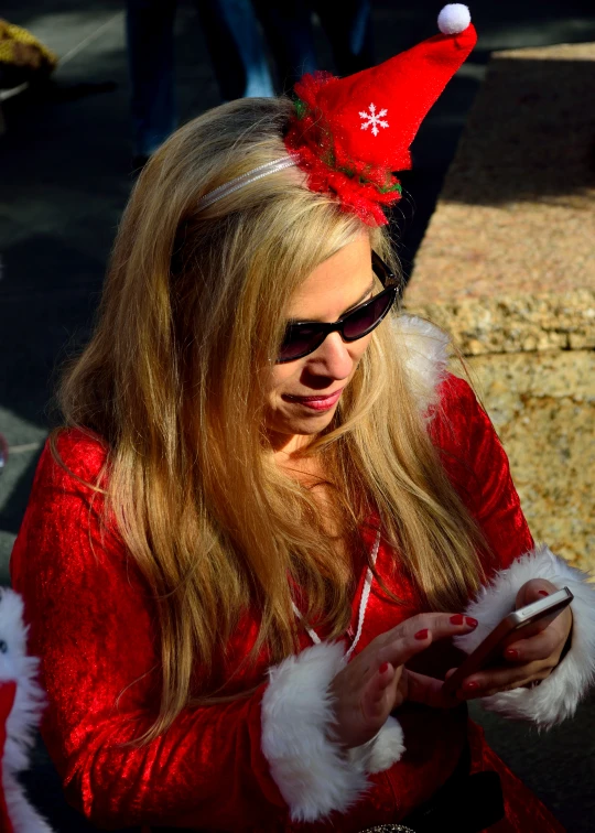 a woman in santa suit is looking at her cellphone