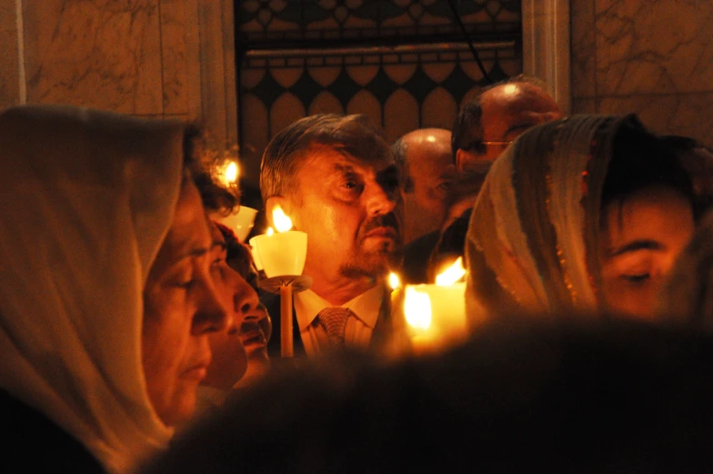 several people are gathered around holding candles