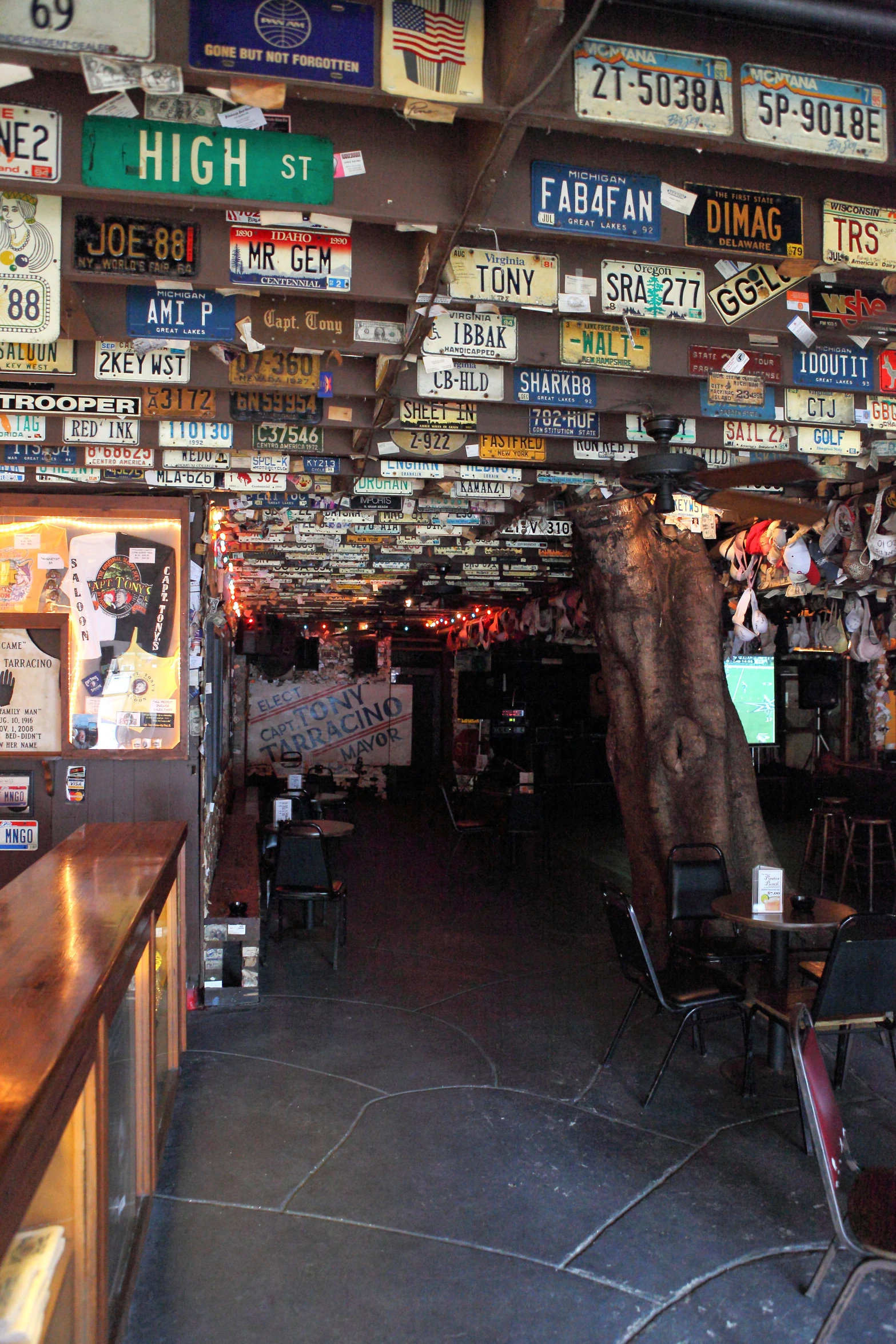 a covered market with tables and bar chairs and many vintage plates on the wall