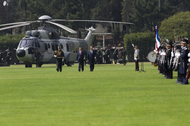 military personnel walking toward a helicopter with people in uniform