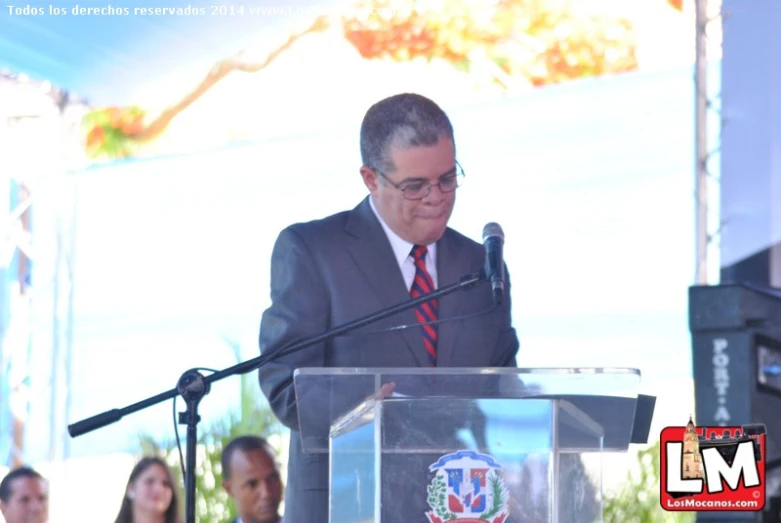 a man in a suit and tie speaking into a microphone