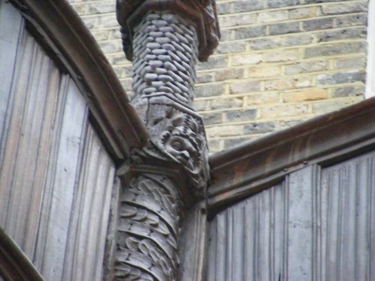 a wooden carving on a stone face in front of a brick building