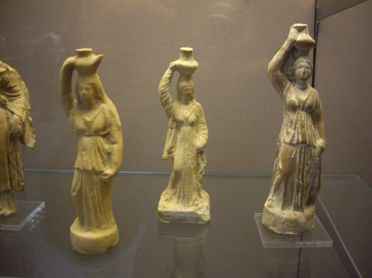 three ancient figurines are displayed in a museum