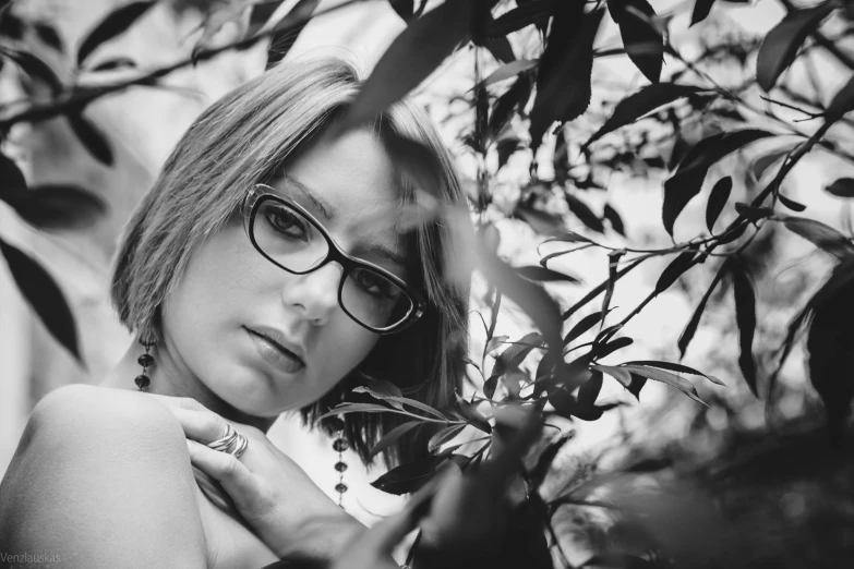 a woman in glasses, leaning against a tree