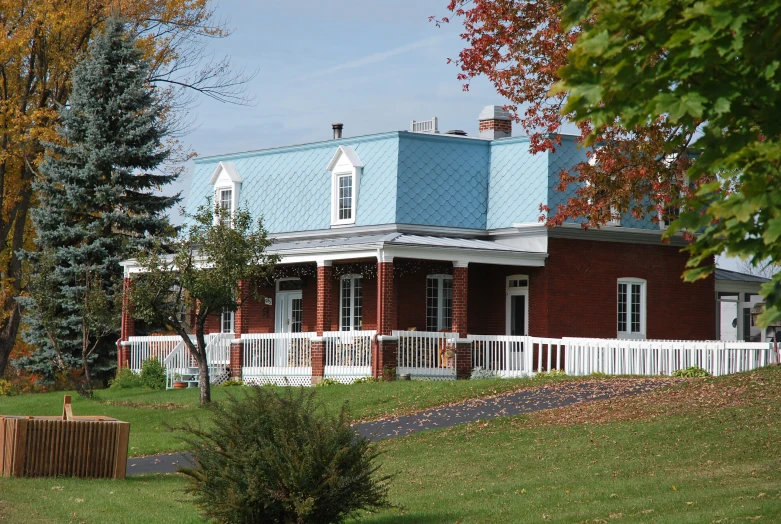 a brick house with a white fence and trees around it