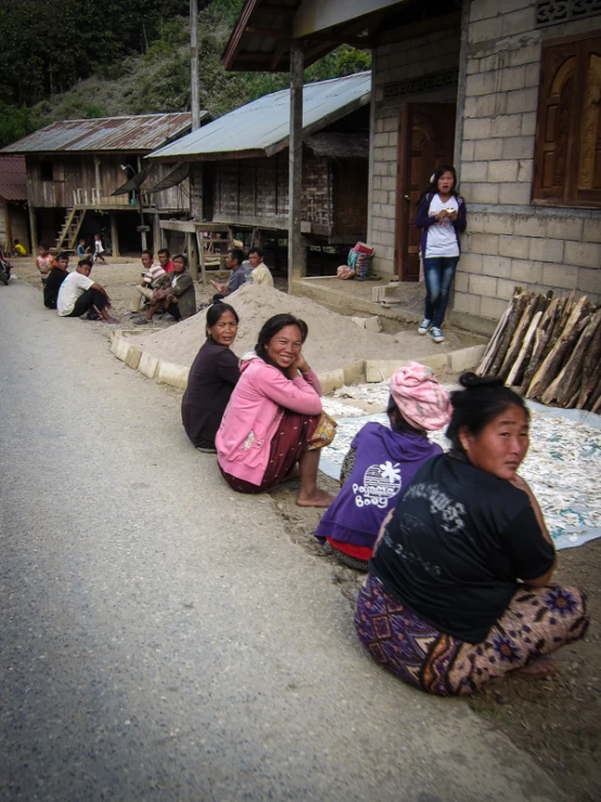 several young women are sitting in front of some houses