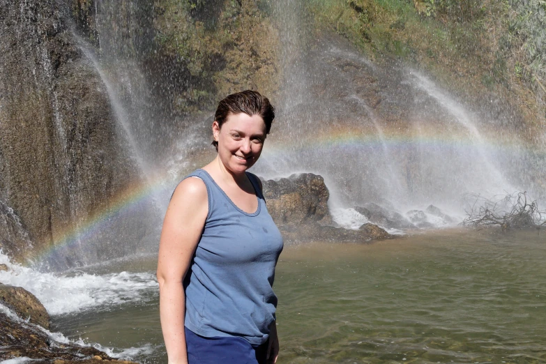 a lady standing near the waterfall in front of the water