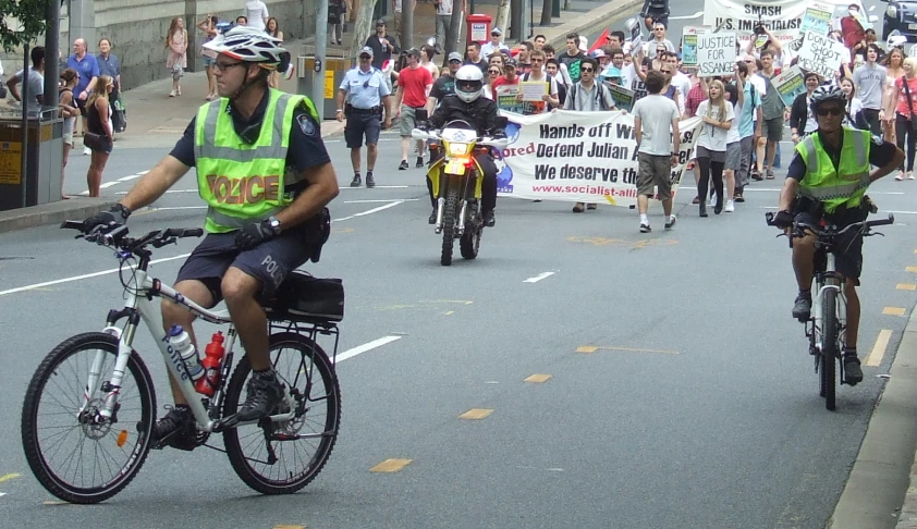 two men riding bicycles down the middle of a street