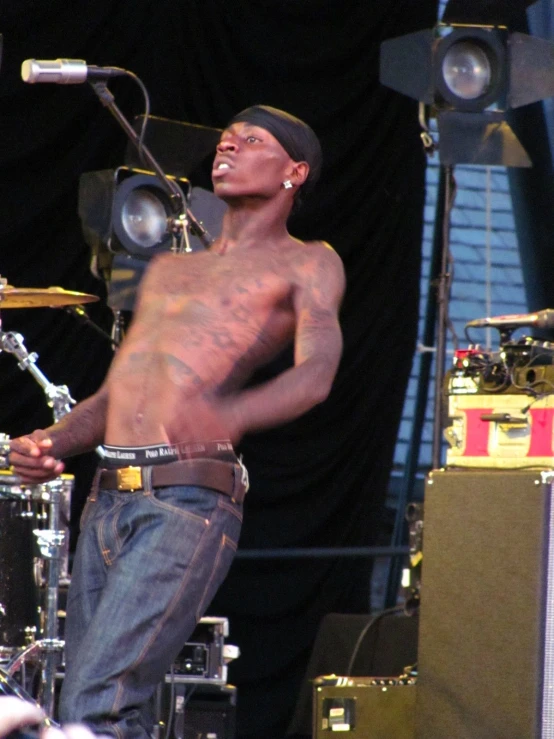 a man without a shirt on, standing next to drums