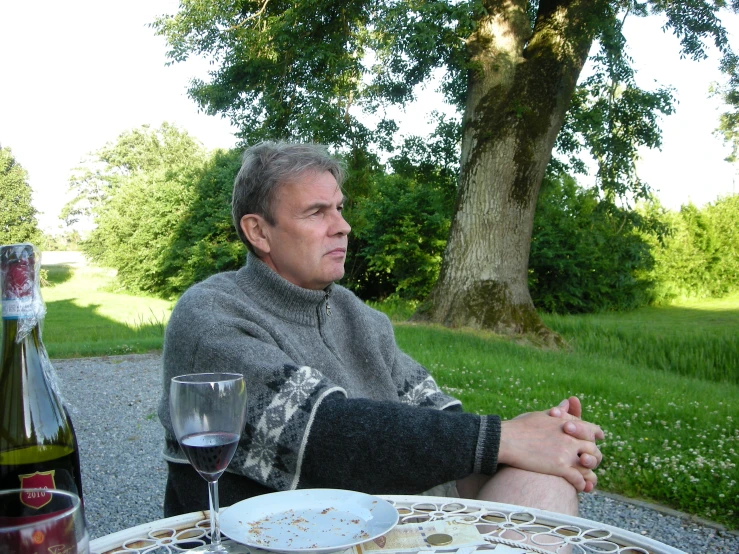 a man sitting at a table holding his drink in his hand