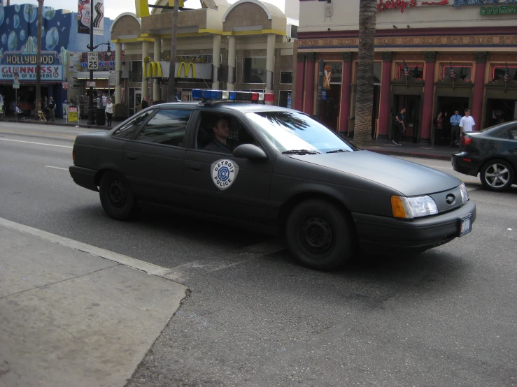 a police car driving down a street past shops