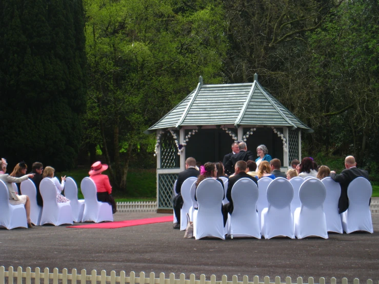 a crowd of people standing next to each other near a gazebo