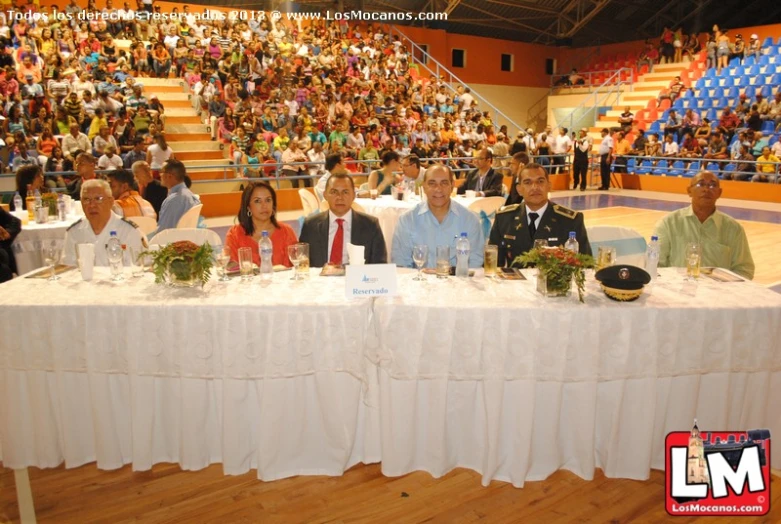 a group of military men and women sitting at a table with large audience