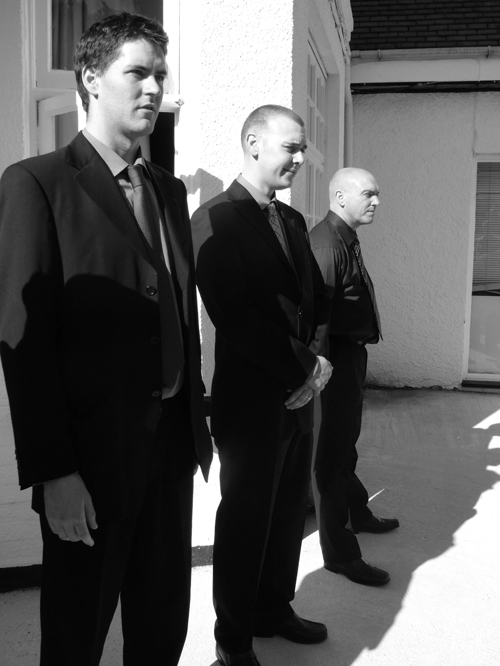 four males standing and looking back with different looks