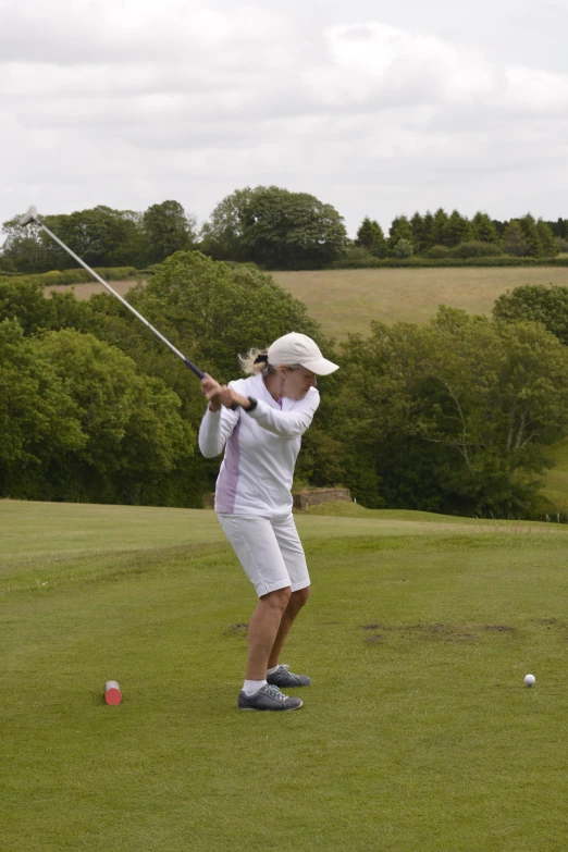 a woman swinging her club at a green golf