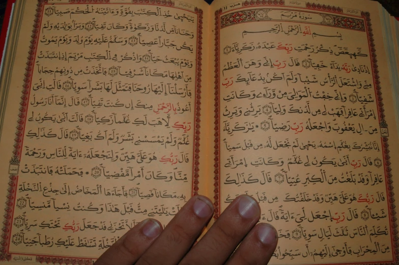 a book in arabic with a hand holding it open