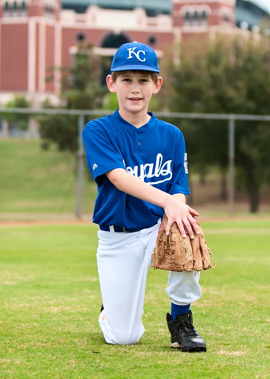 a boy standing on top of a baseball field with a glove